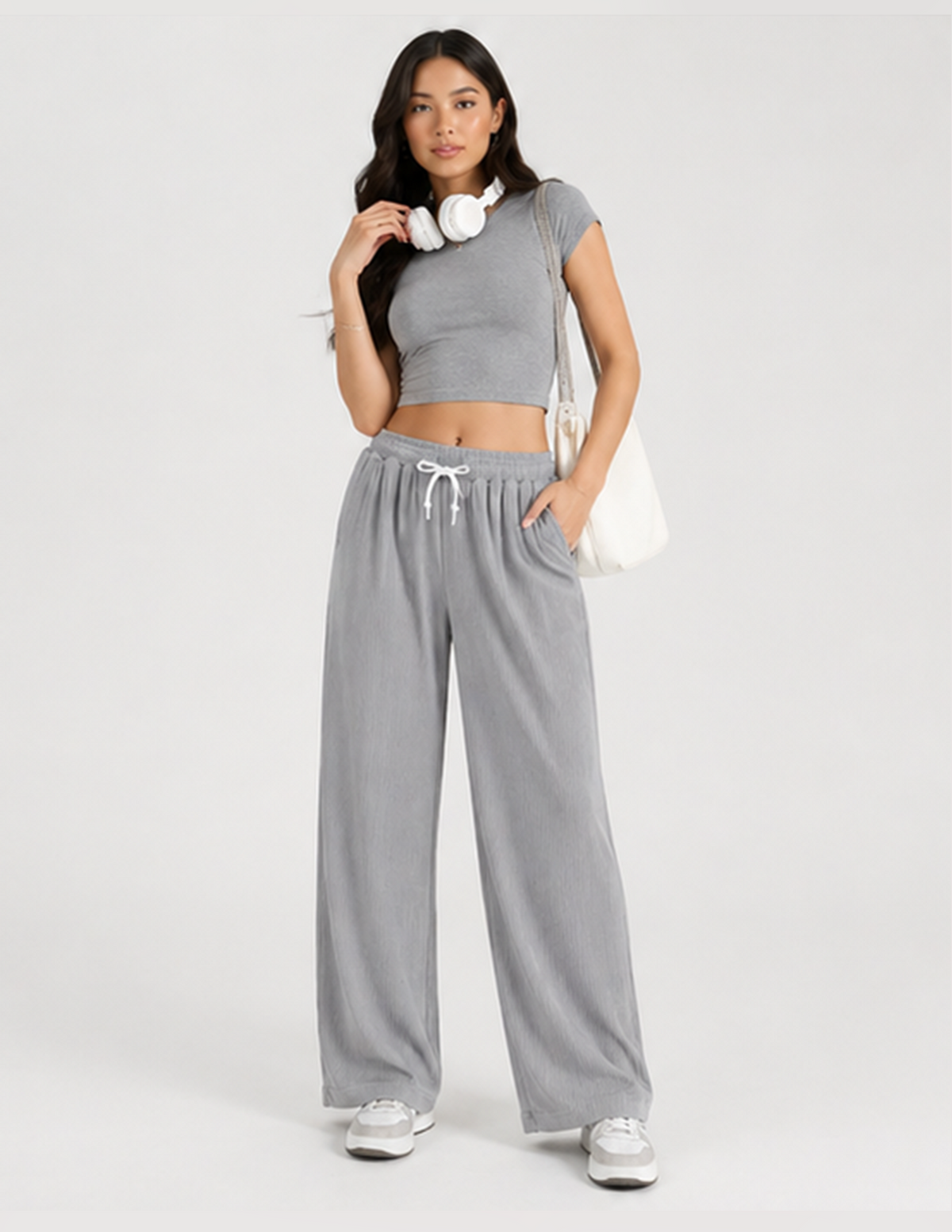 Woman wearing a gray outfit with wide-leg pants and a crop top on a white background