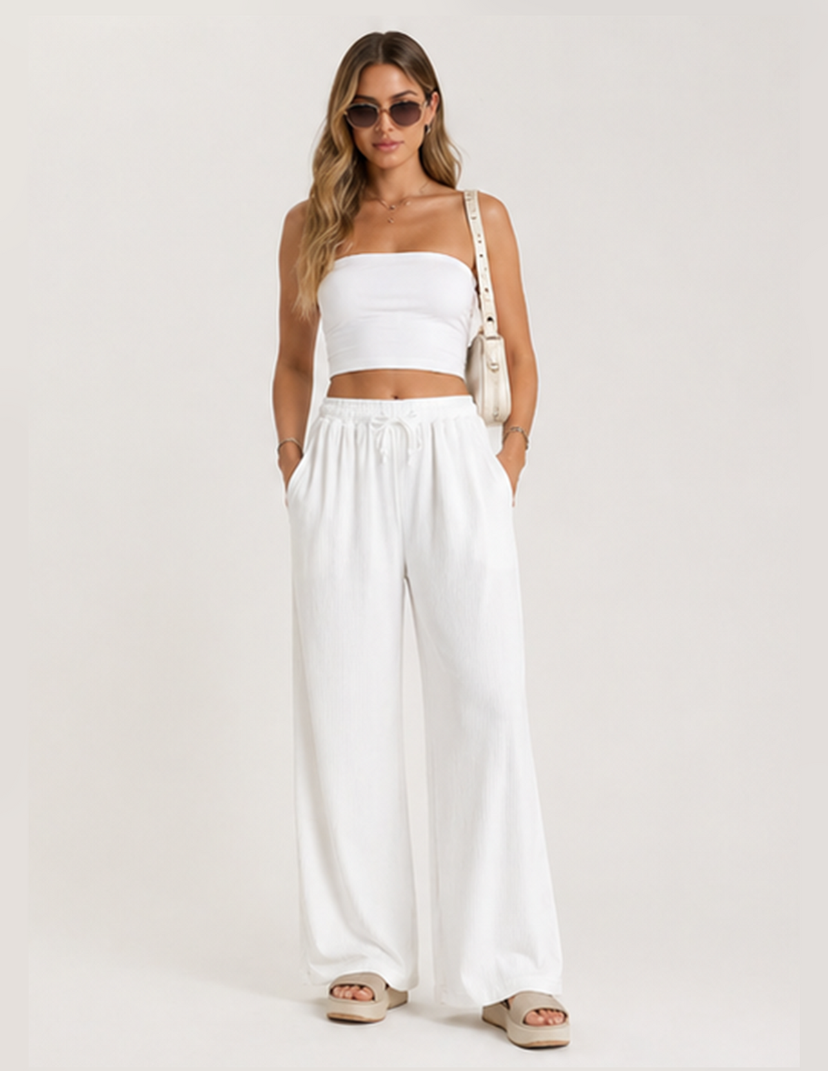 Woman wearing a white outfit with wide-leg pants on a plain background