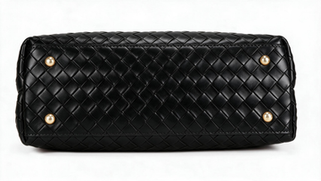 Black woven leather handbag bottom view showing a diamond-quilted pattern and four gold-tone metal studs on a white background.