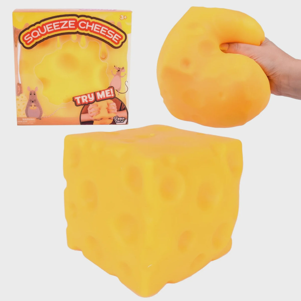 Yellow squishy cheese toy with packaging and a hand squeezing it.