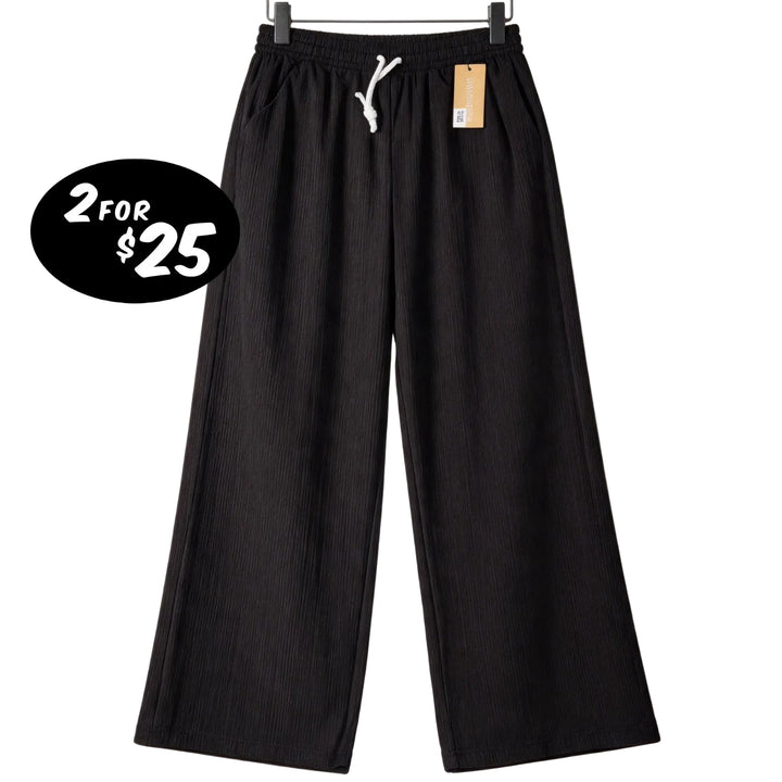 Black wide-leg pants with a price tag on a white background